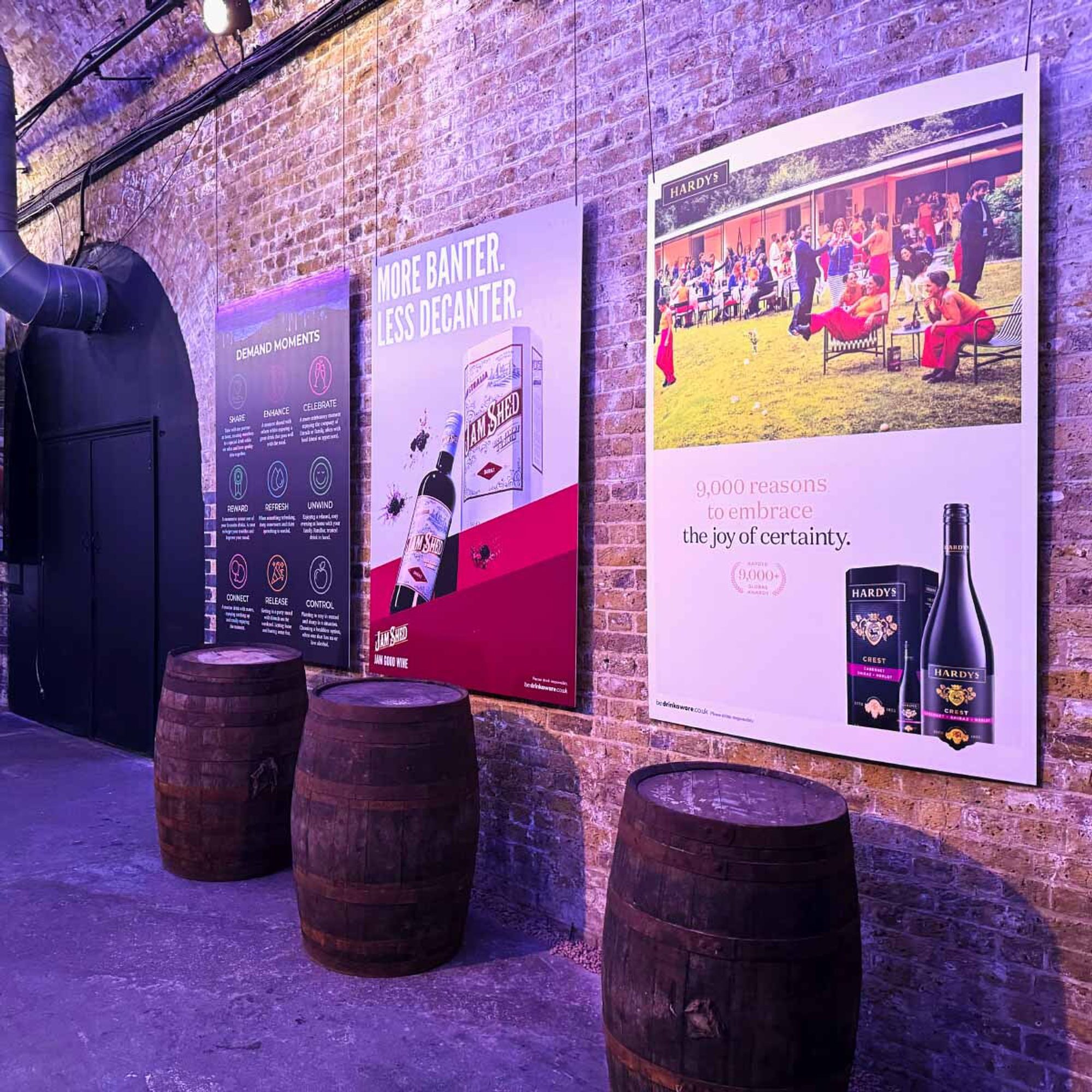 6-sheet posters of Accolade (now Vinarchy) brands mounted to a wall with wine barrels and a colourfully lit warehouse style backdrop.