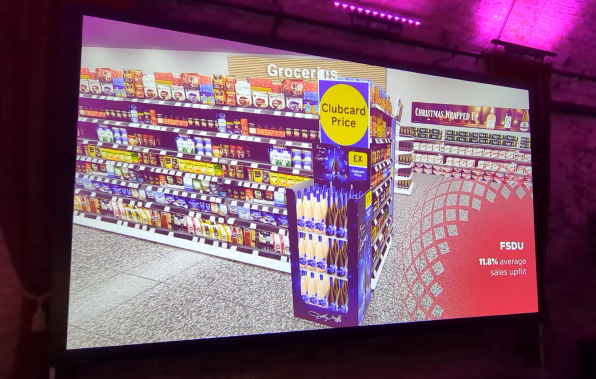 A large format screen showing a 3D fly-through of a Tesco store, featuring Accolade Wines point of sale.